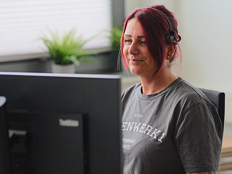 Frau sitzt vor einem Computer und lacht